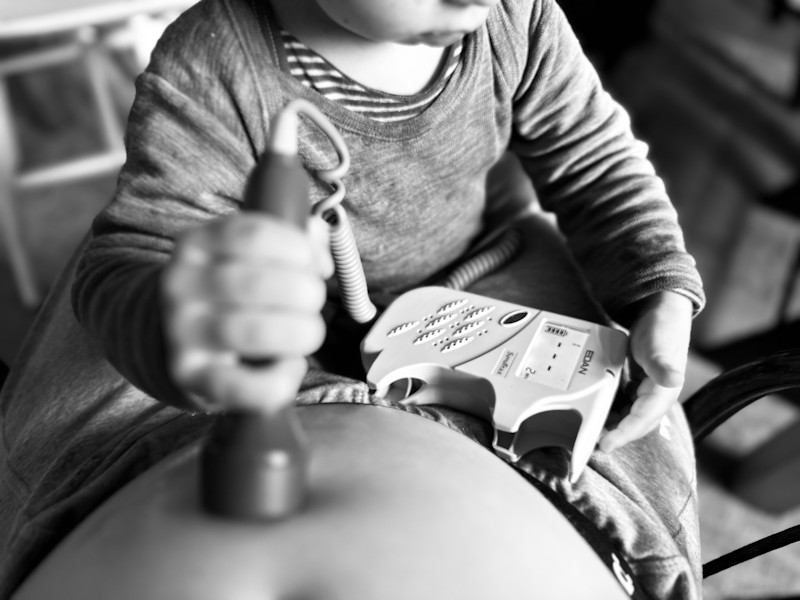 child holds a doptone to listen to babies heartbeat